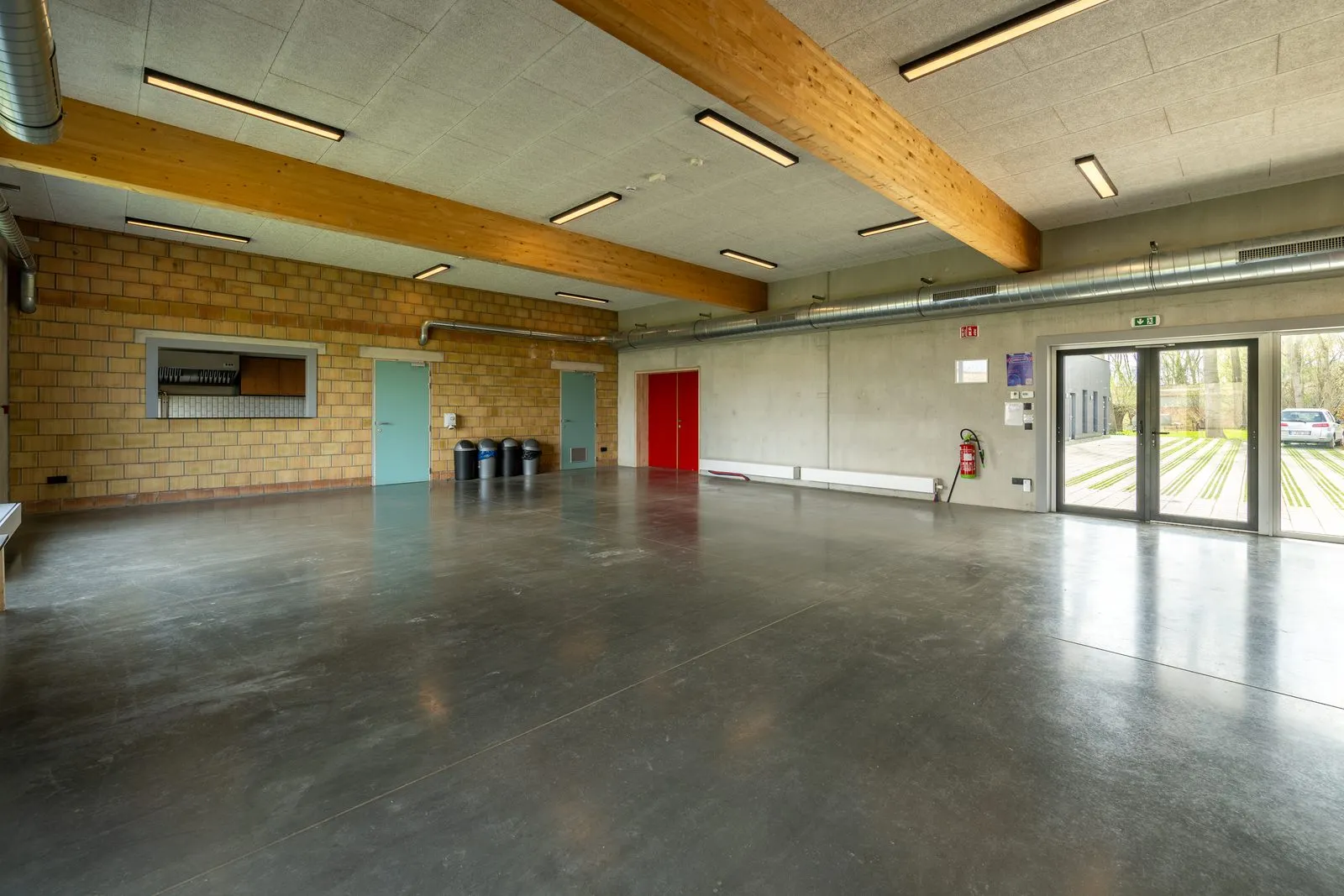 Dezelfde zaal van de andere kant, met de doorgeef naar de keuken in de linkermuur en glazen deuren naar de koer